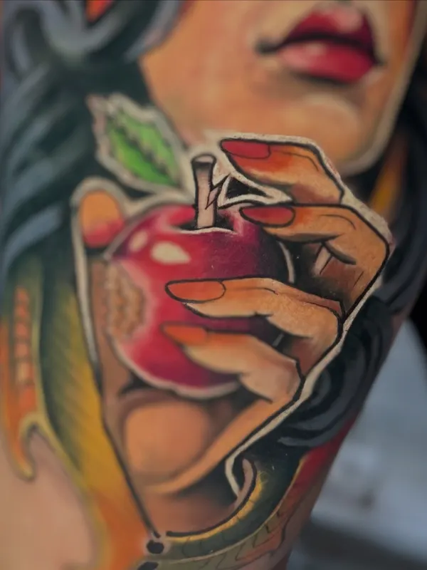 Tatuaje a full color de una mano con una manzana roja, hecho en un estudio de tatuajes de Quito